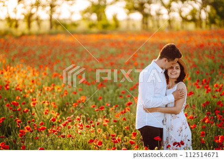 Loving couple in the poppy field at sunset. Enjoying time together. love and lifestyle. Loving couple in the poppy field at sunset. Enjoying time together. love and lifestyle. 112514671