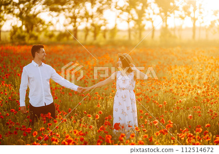 Loving couple in the poppy field at sunset. Enjoying time together. love and lifestyle. Loving couple in the poppy field at sunset. Enjoying time together. love and lifestyle. 112514672