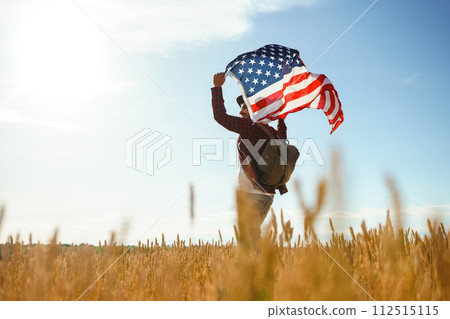4th of July. American Flag. Traveler with the flag of America. The man in a hat, a backpack, a shirt and jeans. 4th of July. American Flag. Traveler with the flag of America. The man in a hat, a backpack, a shirt and jeans. 112515115