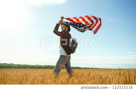 4th of July. American Flag. Traveler with the flag of America. The man in a hat, a backpack, a shirt and jeans. 4th of July. American Flag. Traveler with the flag of America. The man in a hat, a backpack, a shirt and jeans. 112515116