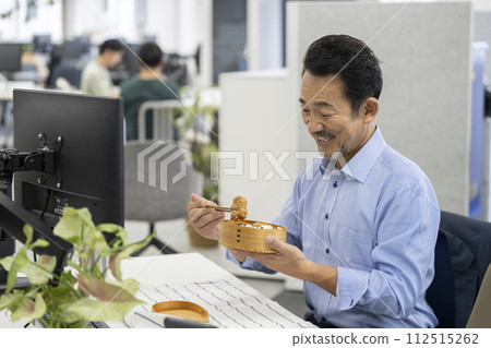 Middle-aged man eating lunch at work Middle-aged man eating lunch at work 112515262