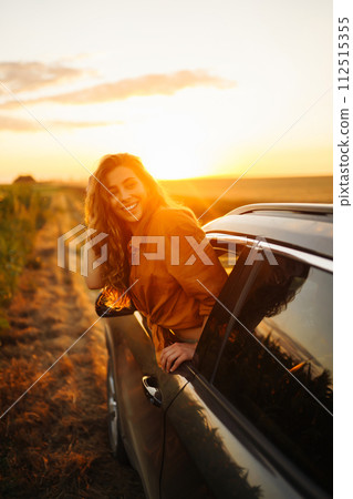 Young woman is resting and enjoying sunset in car. Lifestyle, travel, tourism, nature, active life. 112515355