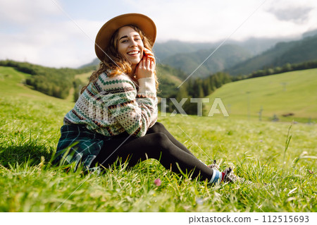Woman walking on through green grass valley on background big mountains. Resting concept. 112515693