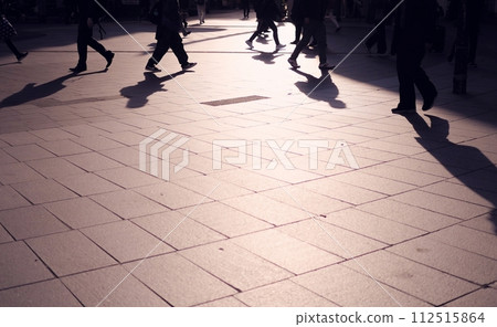 The feet and shadows of people passing by 112515864