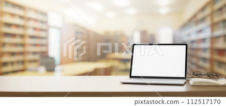 A wooden table features a laptop computer mockup over a blurred background of a school library. A wooden table features a laptop computer mockup over a blurred background of a school library. 112517170
