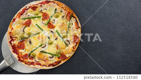 A freshly baked pizza rests on a stone surface, with copy space A freshly baked pizza rests on a stone surface, with copy space 112518580