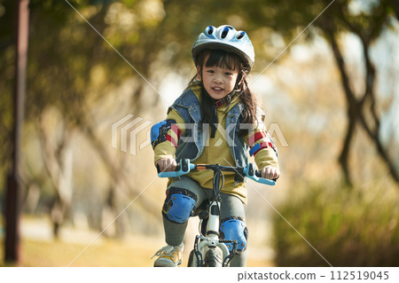 little asian girl riding bike outdoors in city park little asian girl riding bike outdoors in city park 112519045