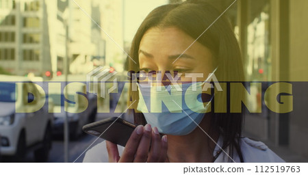 Social distancing text against woman wearing face mask talking on smartphone on the street 112519763