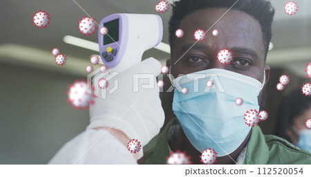 Image of covid-19 cells floating with man having temperature checked wearing face masks 112520054