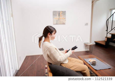 A woman operating a TV remote control 112521339