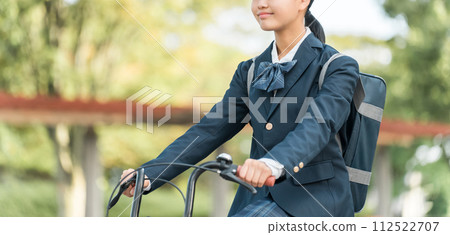 Junior and senior high school girls in uniforms commuting to school by bicycle in the park Junior and senior high school girls in uniforms commuting to school by bicycle in the park 112522707