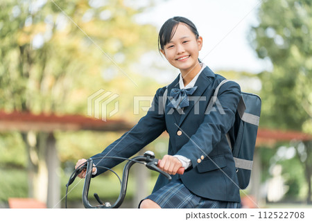 Junior and senior high school girls in uniforms commuting to school by bicycle in the park Junior and senior high school girls in uniforms commuting to school by bicycle in the park 112522708