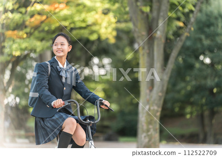 Junior and senior high school girls in uniforms commuting to school by bicycle in the park Junior and senior high school girls in uniforms commuting to school by bicycle in the park 112522709