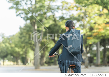 Junior and senior high school girls in uniforms commuting to school by bicycle in the park 112522711