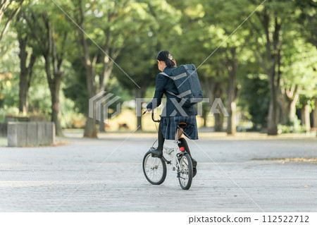 穿著制服的國中和高中女生在公園騎自行車上下學 112522712