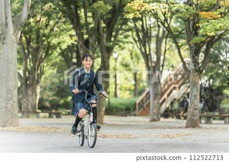 穿著制服的國中和高中女生在公園騎自行車上下學 112522713