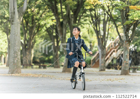 穿著制服的國中和高中女生在公園騎自行車上下學 112522714