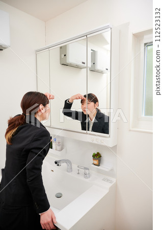 Business woman getting ready in front of the mirror Business woman getting ready in front of the mirror 112523132