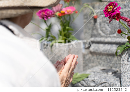 老婦人在墳墓前雙手合十向墳墓祈禱 112523242