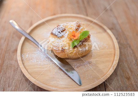 Modern sweet puffs Choux pastry cream puffs (eclairs) on wood plate 112523583