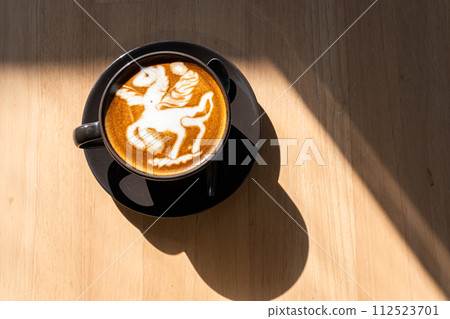Hot coffee latte with latte art in the form of a horse milk foam in cup mug on wood desk on top view. As breakfast In a coffee shop at the cafe,during business work concept 112523701