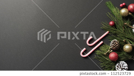 Frohe weihnachten text with candy canes, christmas tree branch and baubles on grey background 112523729
