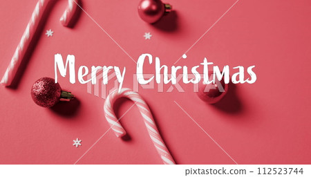 Merry christmas text over candy canes and red baubles on red background 112523744