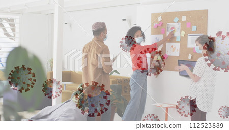 Image of floating covid-19 cells with colleagues in office wearing face masks 112523889