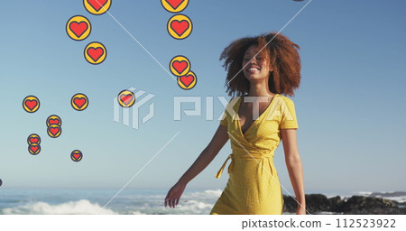 Image of heart digital icons over woman dancing on beach 112523922