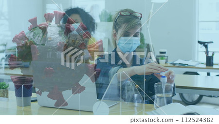 Image of spinning covid-19 cell with colleagues in office wearing face masks 112524382
