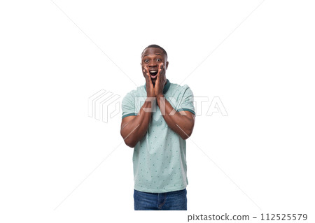 a young surprised african guy with a short haircut dressed in a mint t-shirt and jeans grabbed his a young surprised african guy with a short haircut dressed in a mint t-shirt and jeans grabbed his 112525579