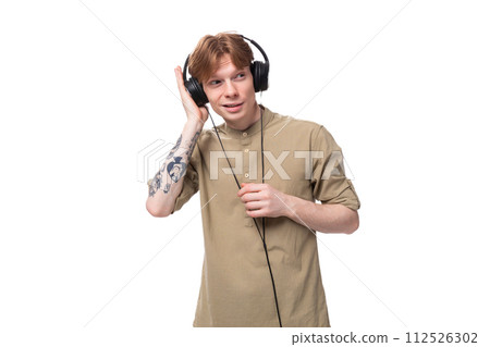 young handsome redhead man in glasses and shirt enjoying music in headphones 112526302