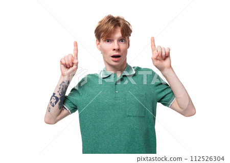 young satisfied happy european guy with red hair with a tattoo on his forearm points his finger at young satisfied happy european guy with red hair with a tattoo on his forearm points his finger at 112526304