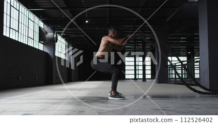 Young biracial man performs squats at a gym 112526402