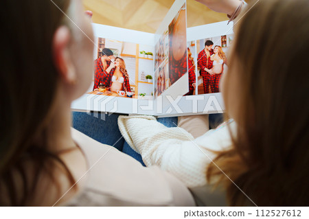 mother and daughter flips through a book with photos of dad and pregnant mom. mother and daughter flips through a book with photos of dad and pregnant mom. 112527612