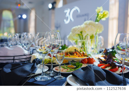 Beautifully set banquet table. Snacks, flowers and wine glasses. 112527636