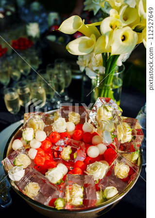 A bowl of ice cubes with frozen flowers and berries. A bowl of ice cubes with frozen flowers and berries. 112527649