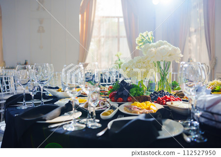 Beautifully set banquet table. Snacks, flowers and wine glasses. Beautifully set banquet table. Snacks, flowers and wine glasses. 112527950