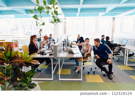 Collaborative process of multicultural skilled young business team during brainstorming meeting in office.Diverse group of young people dressed in formal wear cooperating on developing design project 112528124