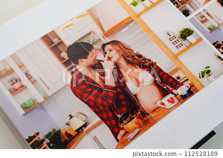 The pages of a photo book with color photos of a pregnant blonde and a man. The pages of a photo book with color photos of a pregnant blonde and a man. 112528189