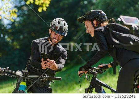A sweet couple, equipped with bicycles and engrossed in coordinating their journey, checks their GPS mobile and watches while planning scenic routes in the park, seamlessly blending technology and A sweet couple, equipped with bicycles and engrossed in coordinating their journey, checks their GPS mobile and watches while planning scenic routes in the park, seamlessly blending technology and 112528241