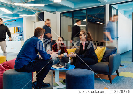 Multiethnic startup business team on meeting in a modern bright open space coworking office. Brainstorming, working on laptop. Group of coworkers walking around in motion blur 112528256
