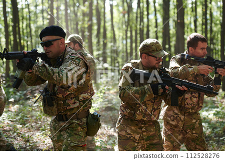 A specialized military antiterrorist unit conducts a covert operation in dense, hazardous woodland, demonstrating precision, discipline, and strategic readiness 112528276