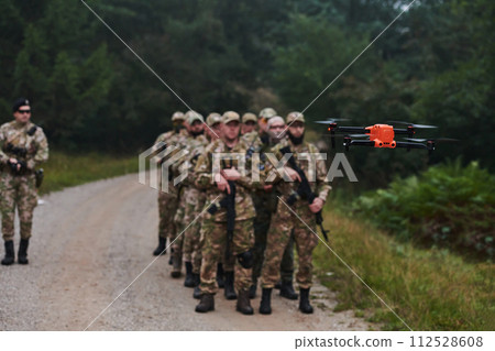 An elite military unit, led by a major, confidently parades through dense forest, showcasing precision, discipline, and readiness for high-risk operations An elite military unit, led by a major, confidently parades through dense forest, showcasing precision, discipline, and readiness for high-risk operations 112528608