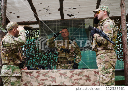 A highly trained military unit strategizes and organizes a tactical mission while studying a military map during a briefing session A highly trained military unit strategizes and organizes a tactical mission while studying a military map during a briefing session 112528661