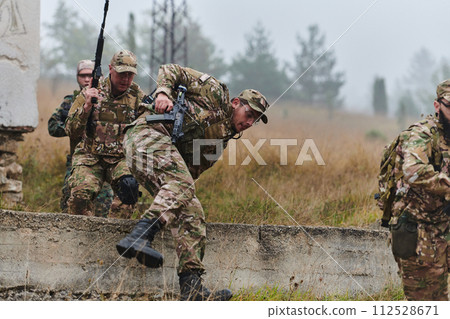 A highly trained elite military unit, clad in camouflage, skillfully navigates through perilous forest terrain, overcoming obstacles and executing a precise and covert mission A highly trained elite military unit, clad in camouflage, skillfully navigates through perilous forest terrain, overcoming obstacles and executing a precise and covert mission 112528671
