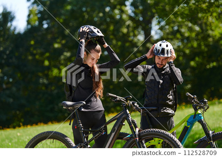 A sweet couple, equipped with bicycles and engrossed in coordinating their journey, checks their GPS mobile and watches while planning scenic routes in the park, seamlessly blending technology and A sweet couple, equipped with bicycles and engrossed in coordinating their journey, checks their GPS mobile and watches while planning scenic routes in the park, seamlessly blending technology and 112528709