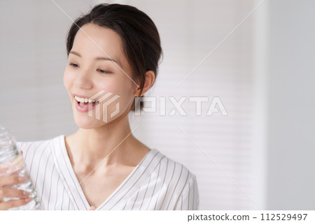 Portrait of a woman in her 30s drinking water 112529497