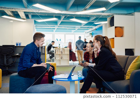 Multiethnic startup business team on meeting in a modern bright open space coworking office. Brainstorming, working on laptop. Group of coworkers walking around in motion blur 112530071