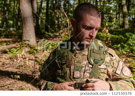 Elite soldier exudes focused determination and readiness, geared up for a perilous military operation, capturing the essence of courage and professionalism in the face of imminent danger Elite soldier exudes focused determination and readiness, geared up for a perilous military operation, capturing the essence of courage and professionalism in the face of imminent danger 112530376